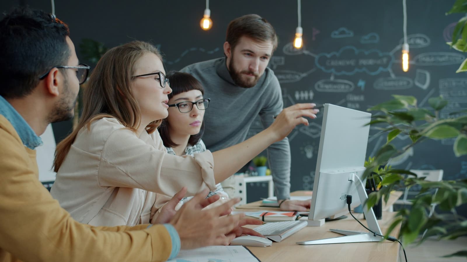Four colleagues reviewing a website design together at a desk