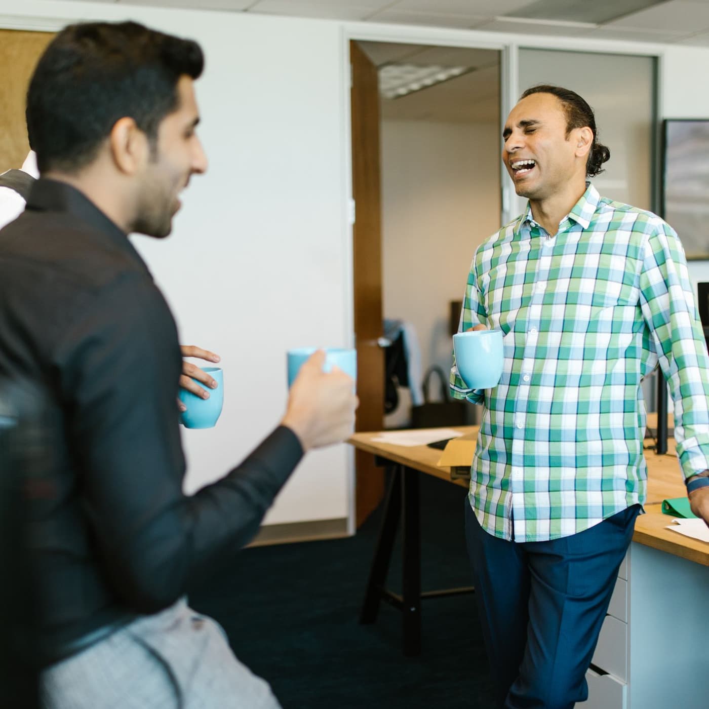 Two colleagues talking over coffee at the office